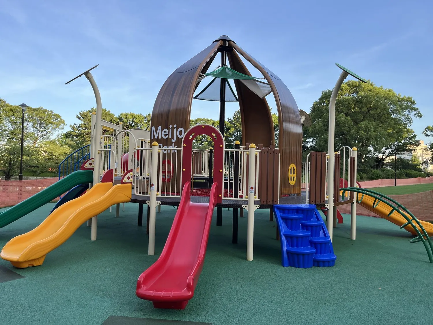 茶色いドーム状の屋根に「Meijo Park」と書かれた大型遊具。緑・黄・赤の3本の滑り台と、青い階段がある